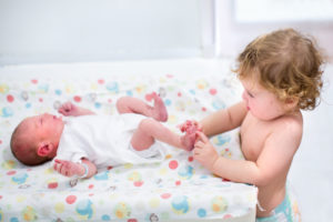 Portrait of a cute curly toddler girl playing with the feet of h